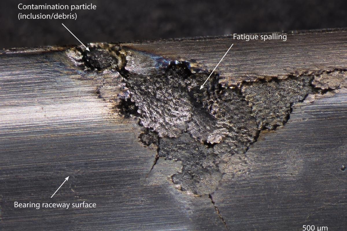 Micrograph showing contamination-induced fatigue spalling on a bearing raceway
